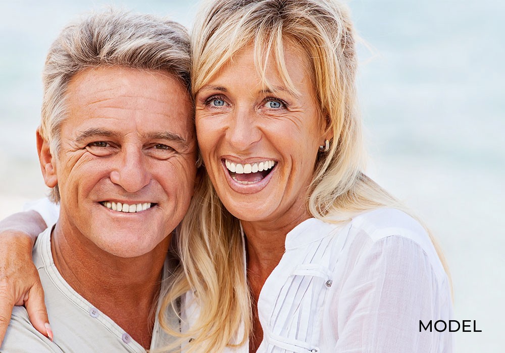 Couple smile after switching from denture to dental implants.